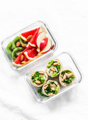 Healthy diet food lunch box - fruit and chicken, beans, green salad pita bread on a light background, top view. Sweet b savory lunch box