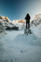 Fototapeta na wymiar Man with backpack trekking in mountains. Cold weather, snow on Peaks