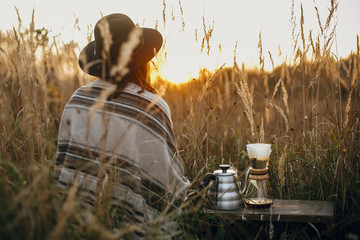 Alternative coffee brewing outdoors in travel. Hipster woman relaxing near hot coffee in filter in...