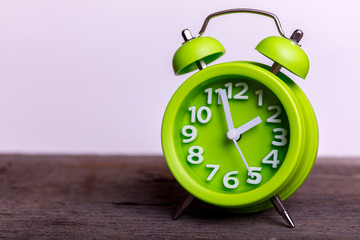 Vintage green retro alarm clock on wood table, with empty space for your text. Classic with double bell.