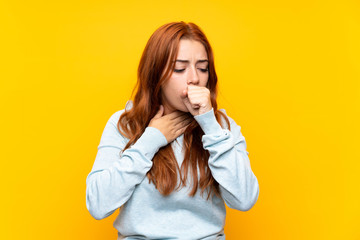 Teenager redhead girl over isolated yellow background is suffering with cough and feeling bad
