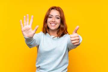 Teenager redhead girl over isolated yellow background counting six with fingers