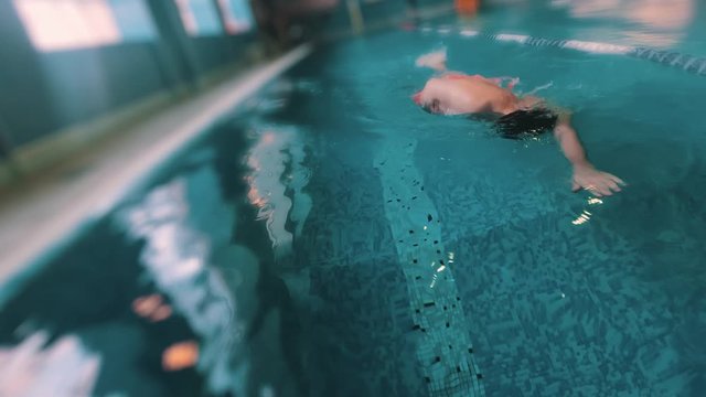 Gimbal shot go pro slow motion of professional swimmer crawling in swimming pool. Professional swimmer in goggles swimming fast training in the pool