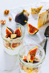 Dessert of sour cream, vanilla, figs, nuts, honey and blue cheese in a glass on a marble background