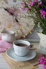 Obraz na płótnie Canvas Tazza di tè con sullo sfondo vaso di fiori e orologio