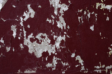 Dark red peeling paint on a concrete wall.
