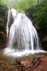 Obraz premium Mountain waterfall surrounded by green plants