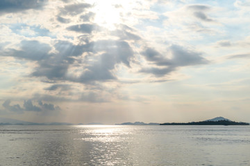 Obraz premium Sunbeams breaking out through the clouds and reaching the calm surface of the sea in Komodo National Park, Indonesia. There are some islands in the back. Island hoping