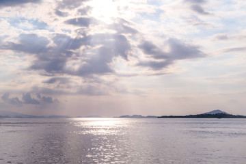Sunbeams breaking out through the clouds and reaching the calm surface of the sea in Komodo National Park, Indonesia. There are some islands in the back. Island hoping