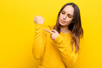 young pretty woman looking impatient and angry, pointing at watch, asking for punctuality, wants to...