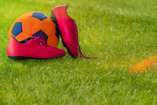 Football shoes and ball on grass.