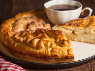  Delicious lemon pie is on a large white plate. Close up. Very tasty homemade cakes. Cup of fragrant tea.