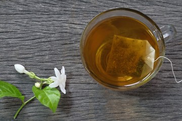 Hot jasmine tea with smoke in a glass on wooden background (top view)