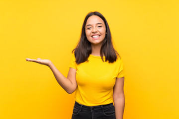 Young brunette girl over isolated background holding copyspace imaginary on the palm to insert an ad