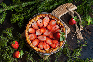 Traditional strawberry pie tart cake sweet baked pastry food on rustic wooden table background with fir branches. Menu or cook book cover concept, horizontal format