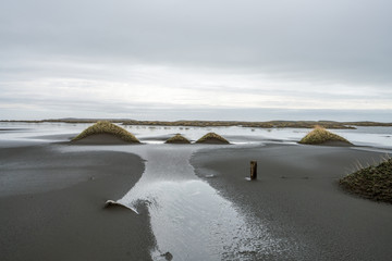 Leading lines towards sandy dunes on the black sandy textured beach of Stokksnes in the Hofn area in Iceland. Art and photography concept.