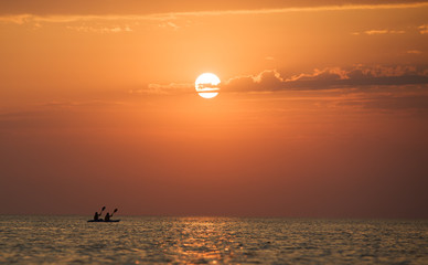 Seascape of still sea surface, man on boat and golden sunset in sky on summer clear day. Still landscapes of travels and destination scenics