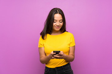 Young brunette girl over isolated background sending a message with the mobile