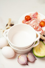 breakfast ingredients: eggs and different vegetables, bacon on a white background