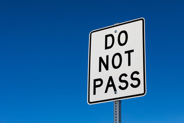 Closeup angled view of do not pass reflective sign. Isolated on deep blue sky background.