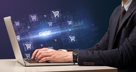Fototapeta na wymiar Businessman working on laptop with SHOP inscription, online shopping concept