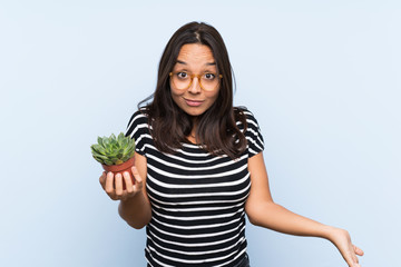 Young brunette woman holding a plant with shocked facial expression