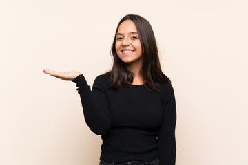 Young brunette woman with white sweater over isolated background holding copyspace imaginary on the...
