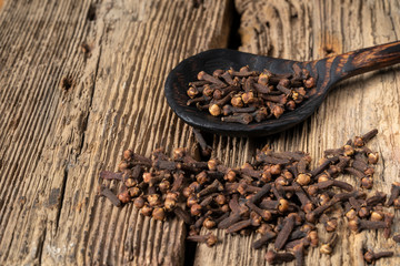 Wooden spoon with cloves on rustic table