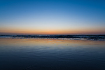 Fototapeta na wymiar Colorful sunset reflected in a wet sandy beach