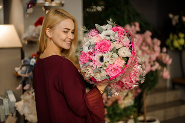 Smiling blond girl enjoying her flower bouquet