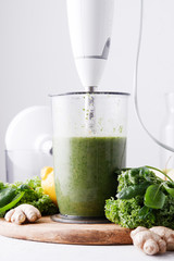 Cooking green smoothie in a blender on a light background. Close up. Fresh green smoothie in a blender. Top view. Freshly prepared vegetarian smoothies from shpenata cabbage and kale.