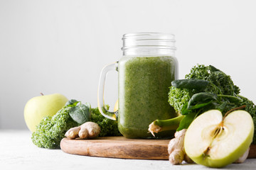 Freshly prepared jar of green smoothie, close up. Fresh vegetable smoothie on a light background. Vegetable smoothie with spinach and kale cabbage.