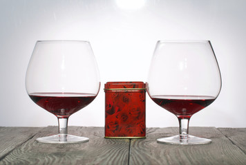Glasses with red dry wine. Gift in a box. Stand on wooden boards. Shot in backlight.