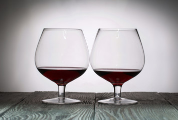 Glasses with red dry wine. Stand on wooden boards. Shot in backlight.