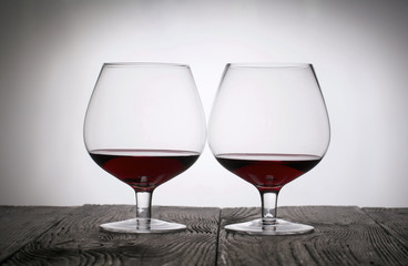 Glasses with red dry wine. Stand on wooden boards. Shot in backlight.