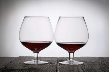 Glasses with red dry wine. Stand on wooden boards. Shot in backlight.