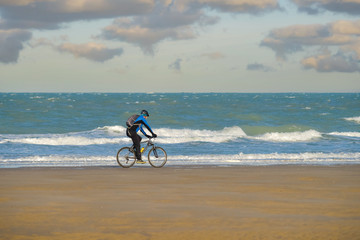 Fototapeta premium nice view of the coast with man mountain biking on the beach