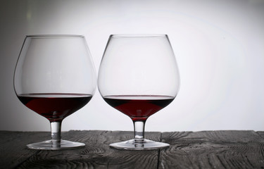 Glasses with red dry wine. Stand on wooden boards. Shot in backlight.