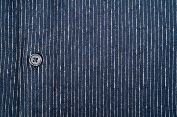 The texture of a denim shirt in dark blue with a small strip, on buttons