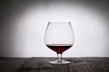 A glass of dry red wine. Stands on wooden boards. Shot in backlight.
