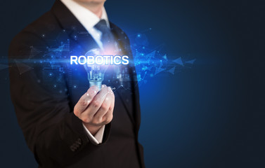 Businessman holding light bulb with ROBOTICS inscription, innovative technology concept