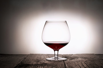 A glass of dry red wine. Stands on wooden boards. Shot in backlight.