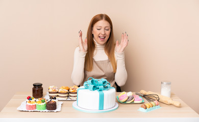Obraz na płótnie Canvas Young redhead woman with a big cake laughing