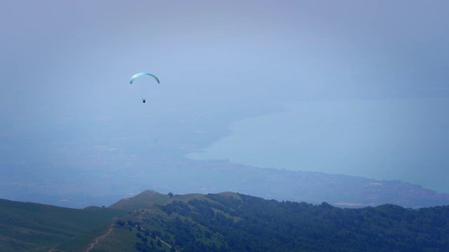 Man flying with paraglider in mountain area, Monta Baldo, Veneto, Italy