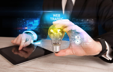 Businessman holding lightbulb with WEB TRAFFIC inscription, online security idea concept