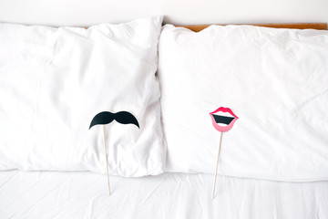 Props with lips for women and mustache for men for a stick party lie on the pillows. Content for honeymooners and lovers for Valentine's Day.