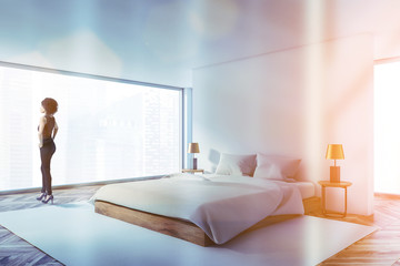 Woman in luxury white master bedroom