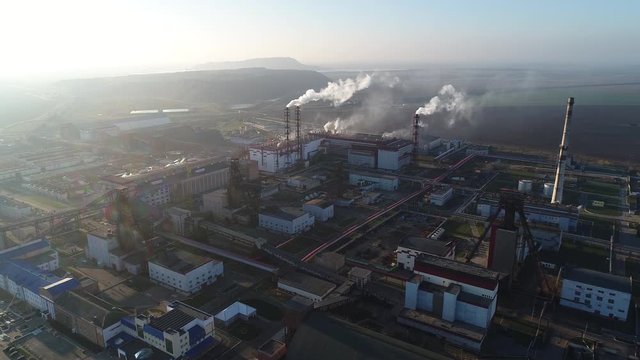 Potash plant for the extraction of potash fertilizers, mountains of waste near the plant, smoke from pipes, shooting from a height, the camera moves toward the subject