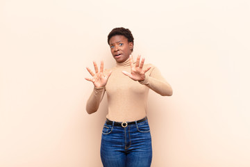 young pretty black womanfeeling terrified, backing off and screaming in horror and panic, reacting...