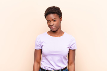 young pretty black womanlooking happy and friendly, smiling and winking an eye at you with a...
